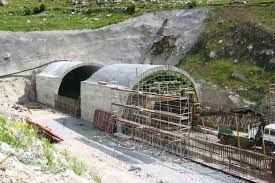 Construcció d'un túnel en un vessant, amb arcs de formigó, bastides i un camió.