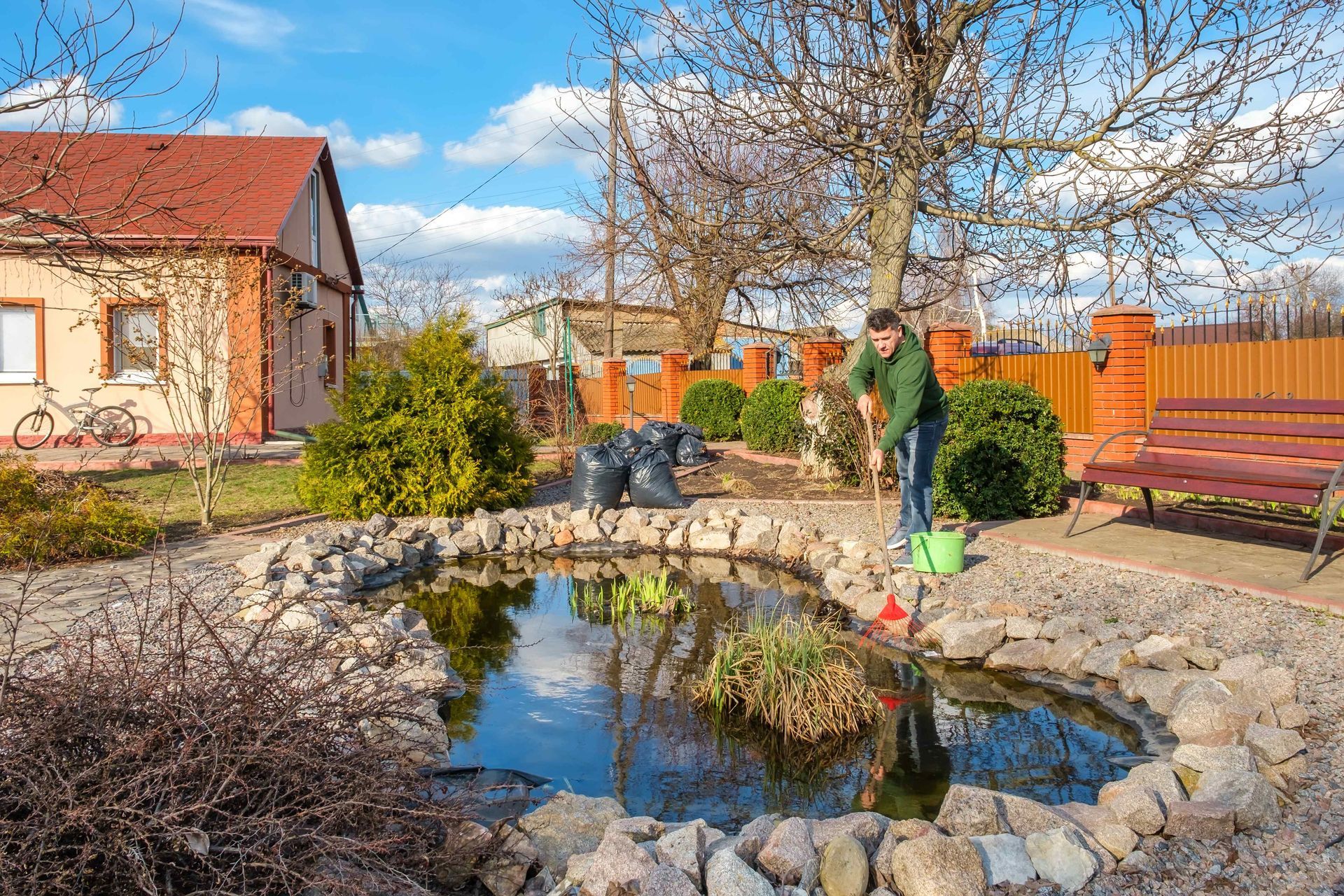 A man cleaning out a garden pond surrounded by natural stones