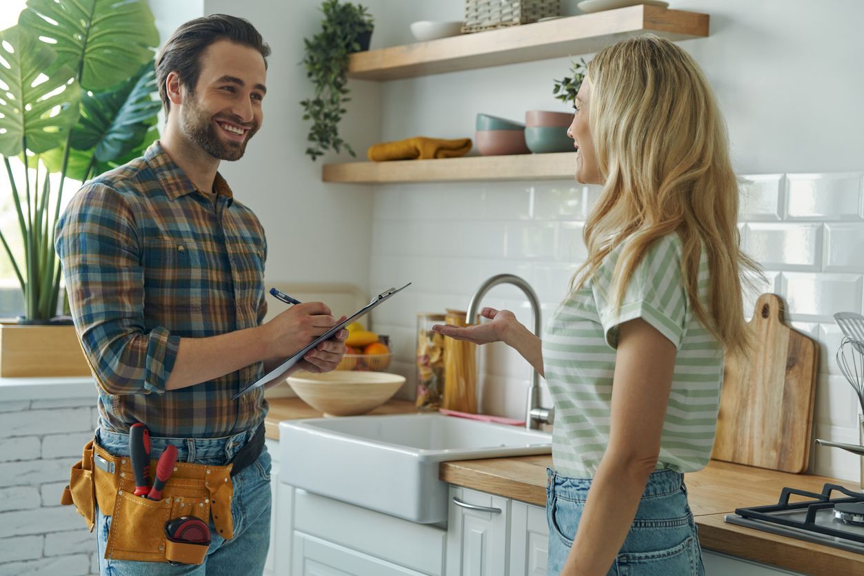 A beautiful homeowner is talking to a male plumber for rough-in plumbing