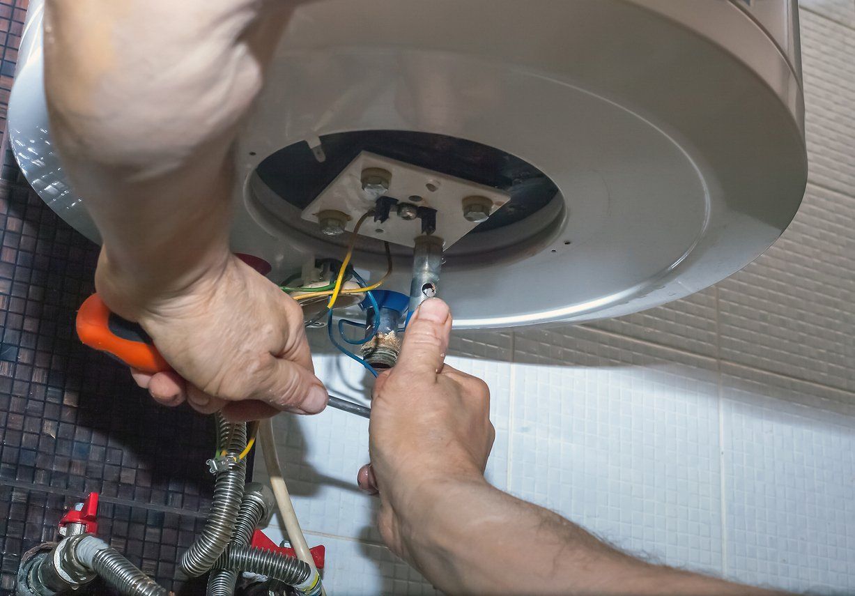 Professional plumber fixing a residential home bathroom's water heater leaks using different tools.