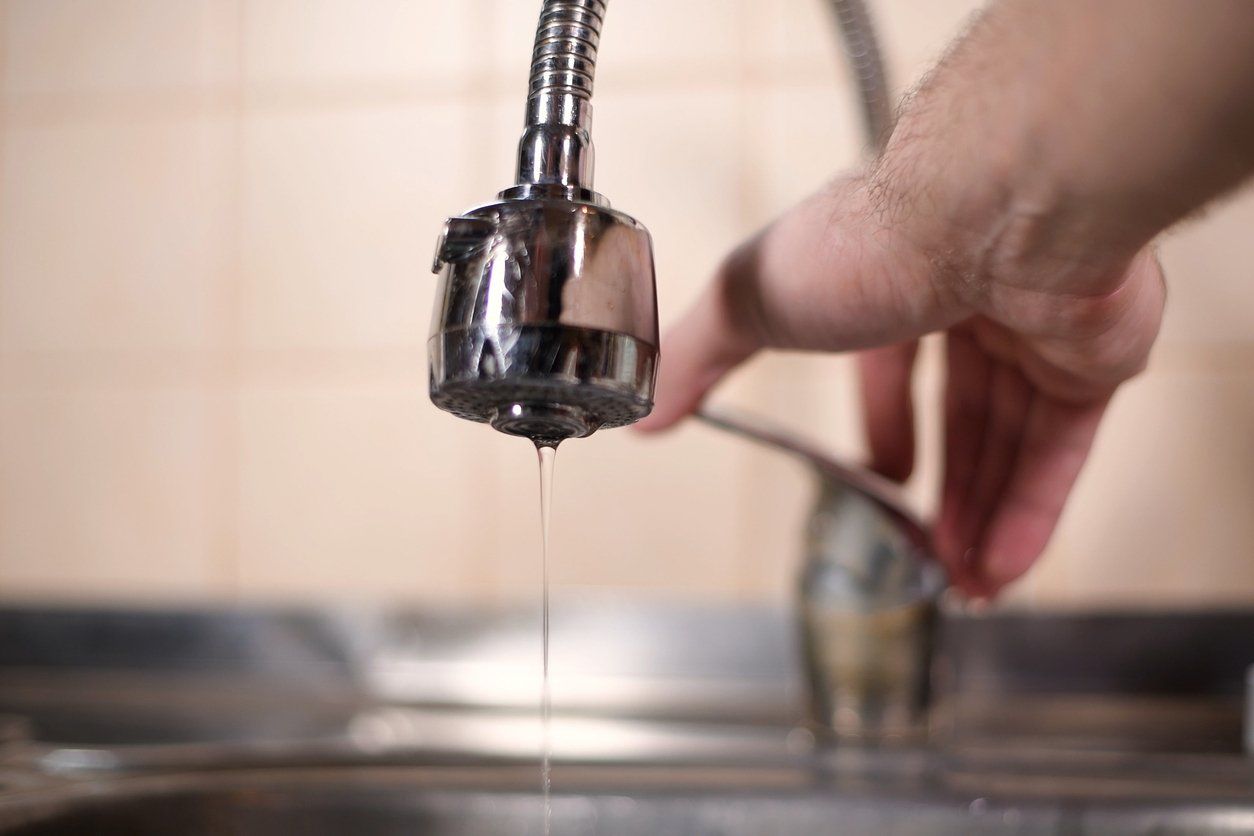 Homeowner checking his home's water supply by turning on the water in his kitchen's faucet.