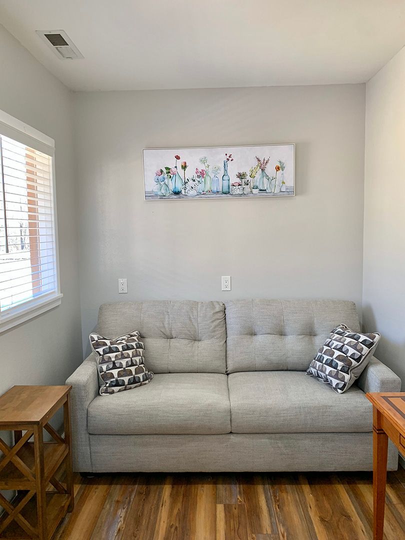 There is a painting on the wall above the couch in the living room.