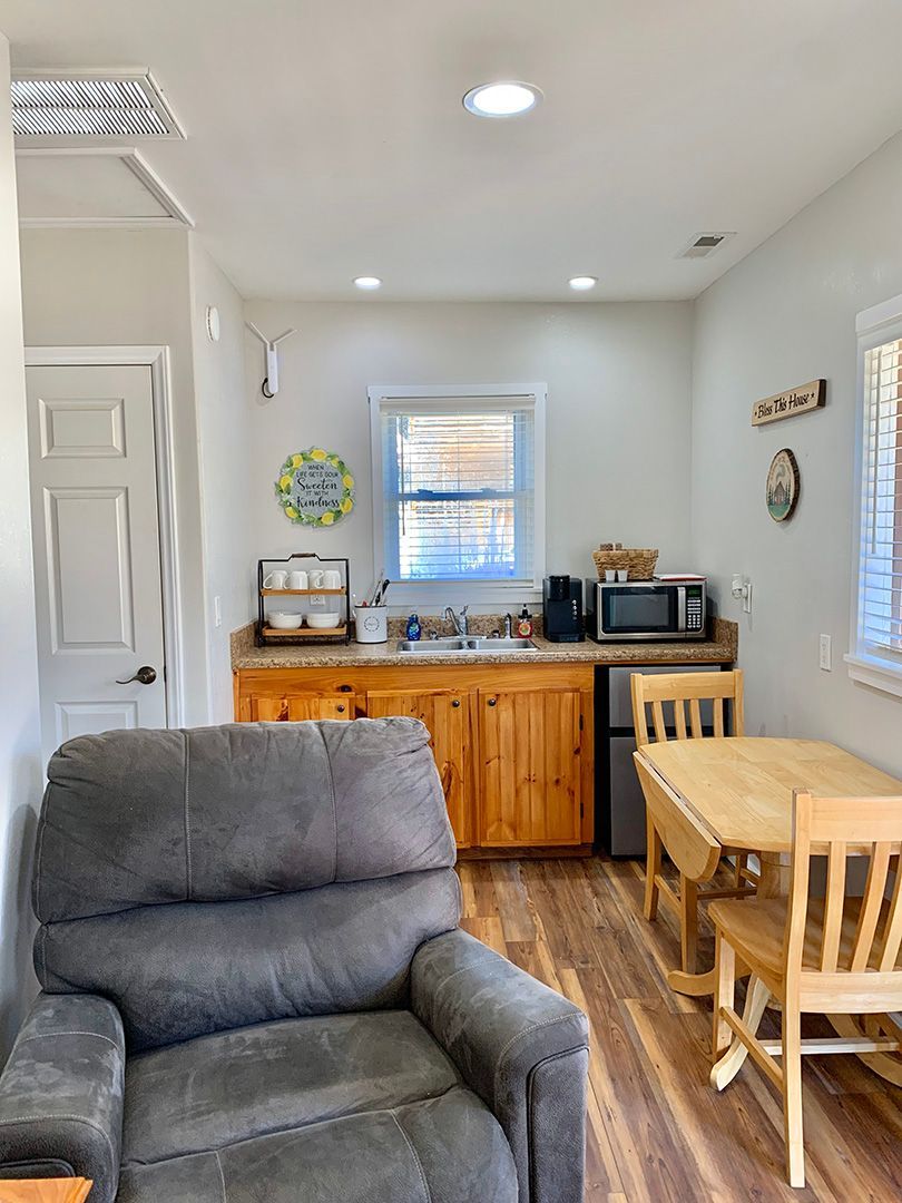 A living room with a couch , table and chairs and a kitchen.