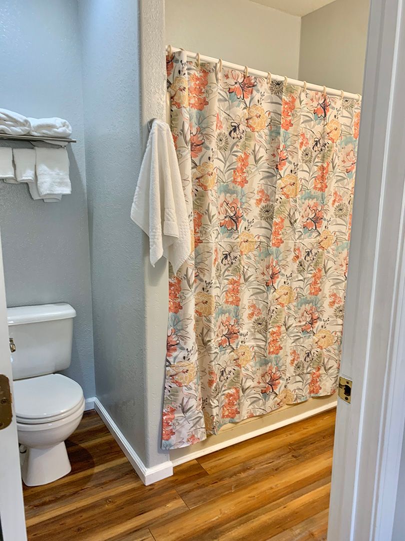 A bathroom with a toilet , shower curtain , and towel rack.