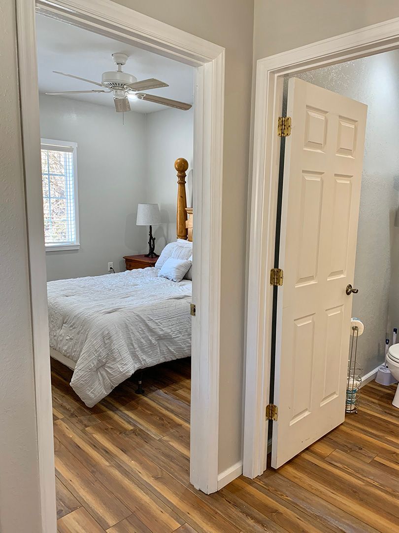 A bedroom with a bed , ceiling fan , and hardwood floors.