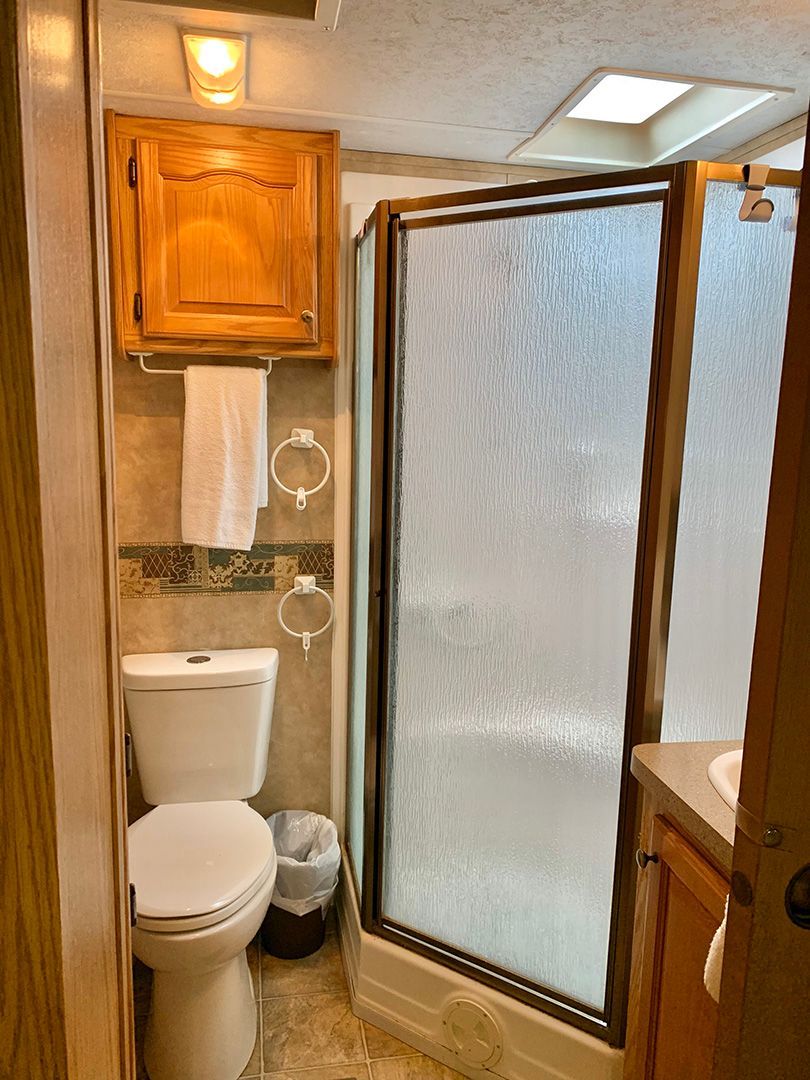 A bathroom with a toilet , sink and shower.