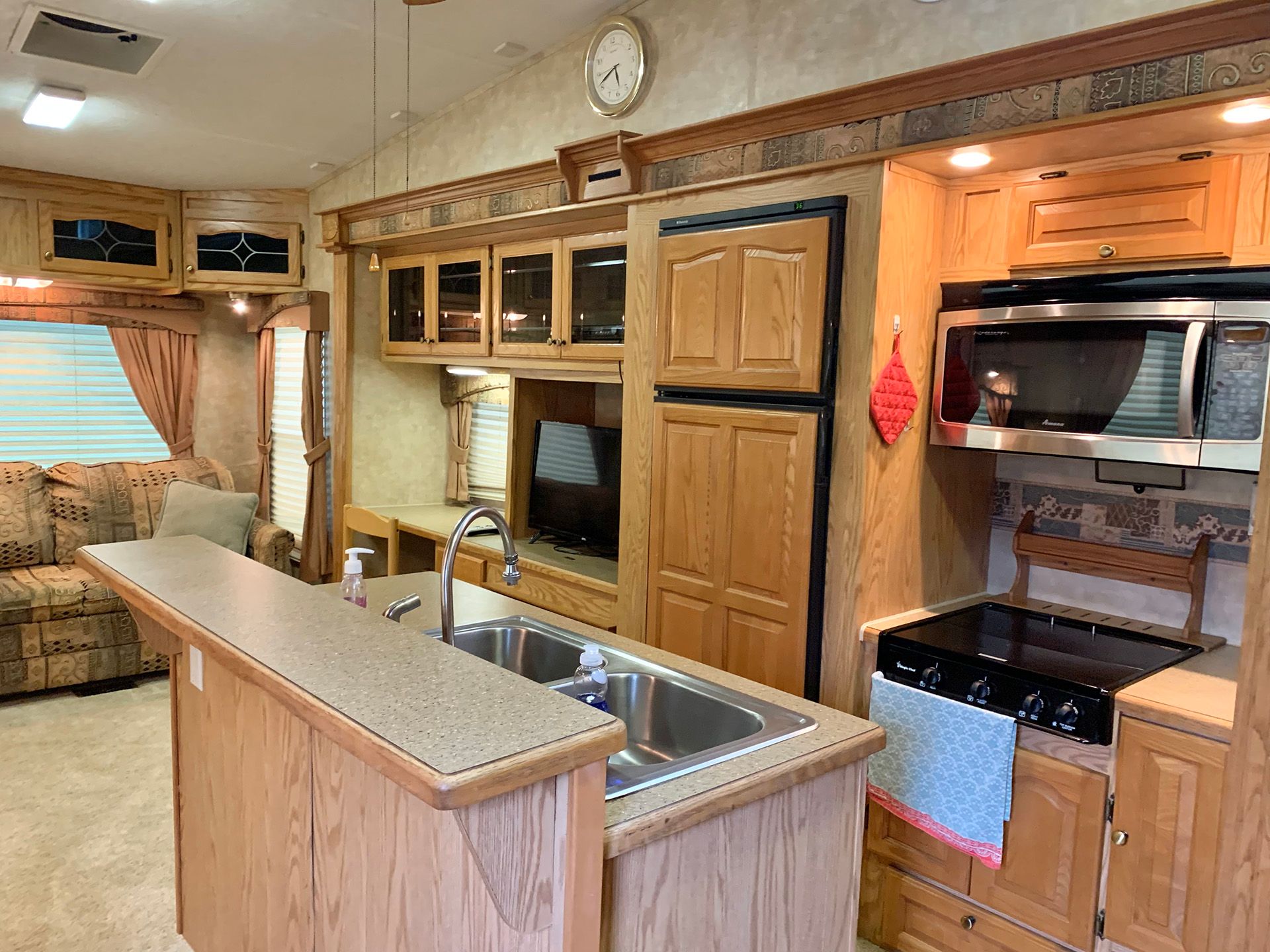 A kitchen in a mobile home with a sink , stove , refrigerator and microwave.