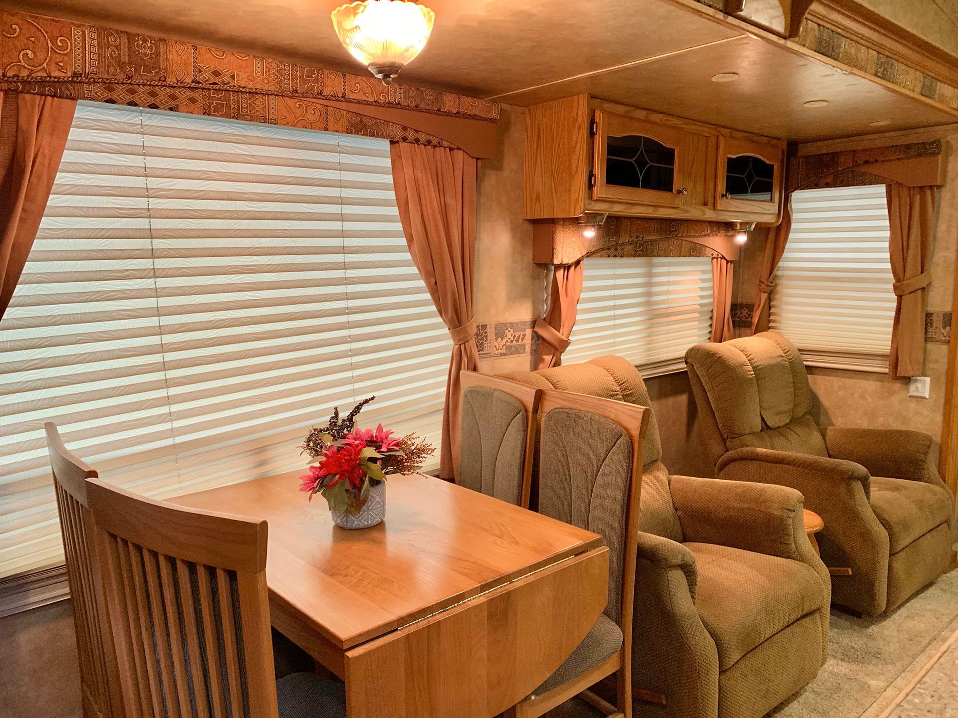 A dining room in a rv with a table and chairs.