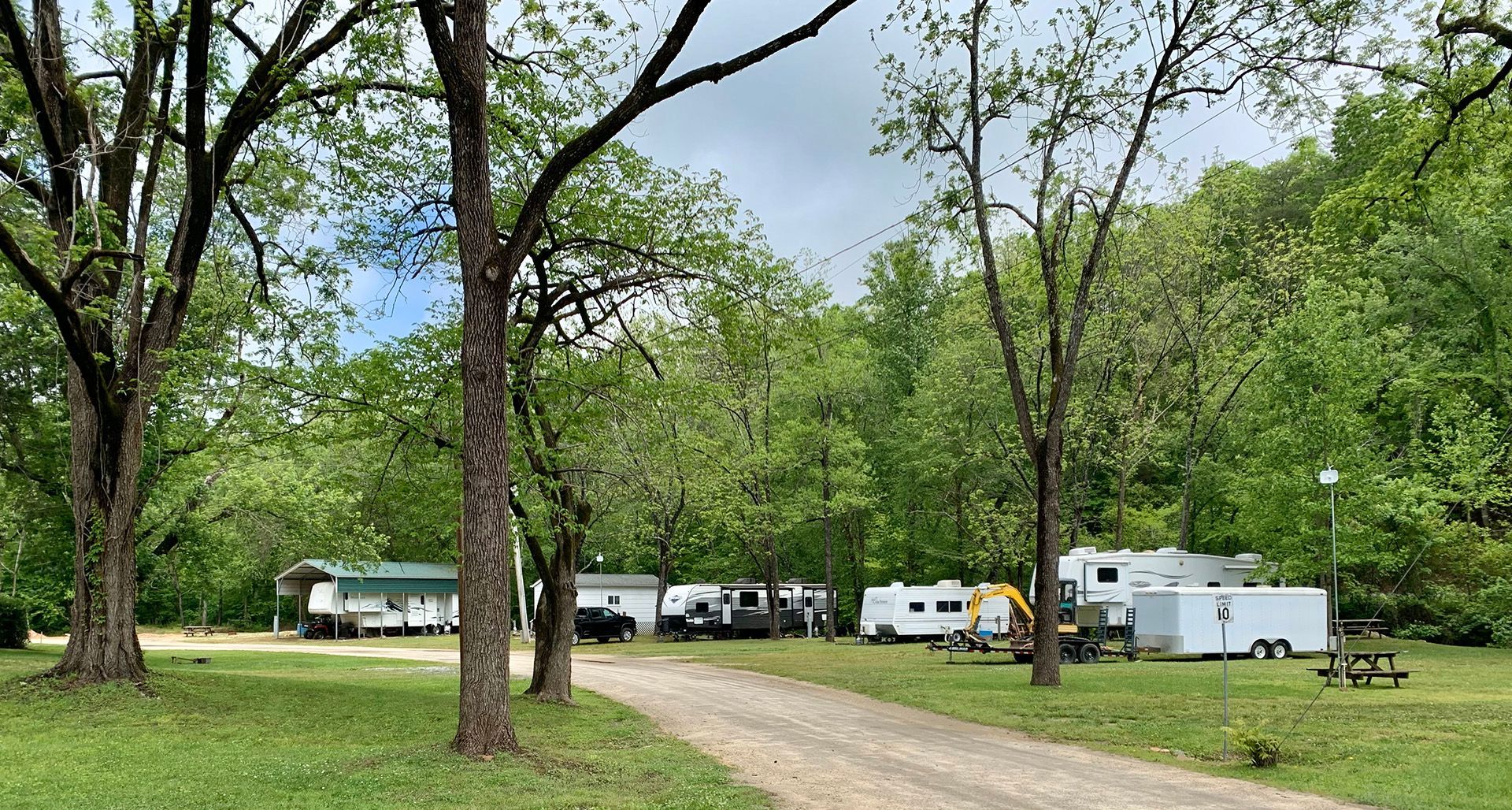 A dirt road leading to a campground filled with rvs and trailers.