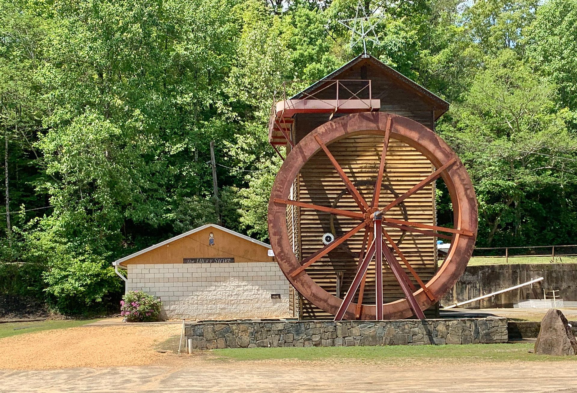 A large wooden water wheel is sitting in front of a building.