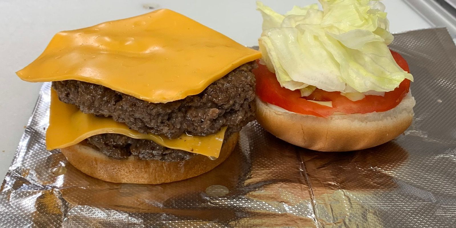 A double cheeseburger with lettuce , tomato and cheese on a bun.