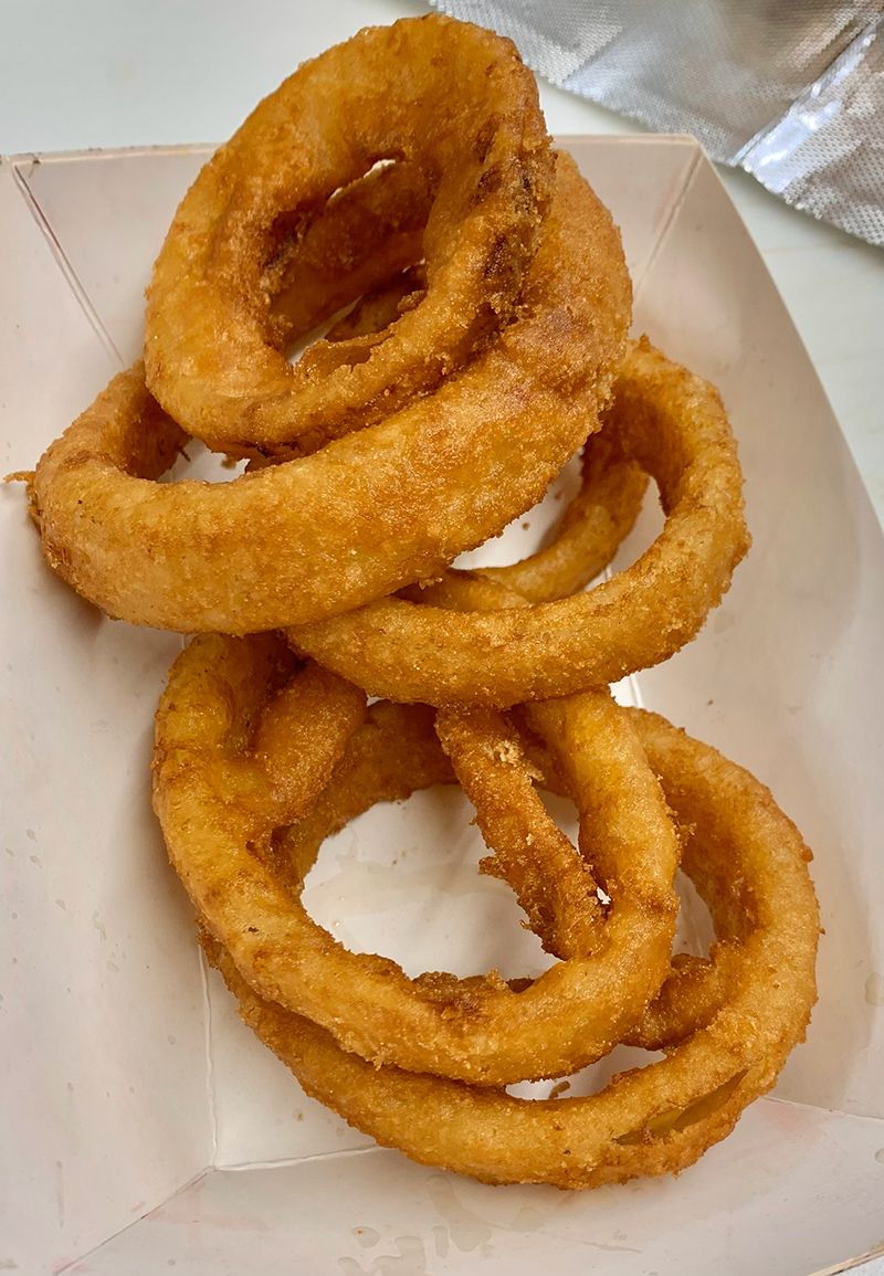 Three onion rings are stacked on top of each other on a paper plate.