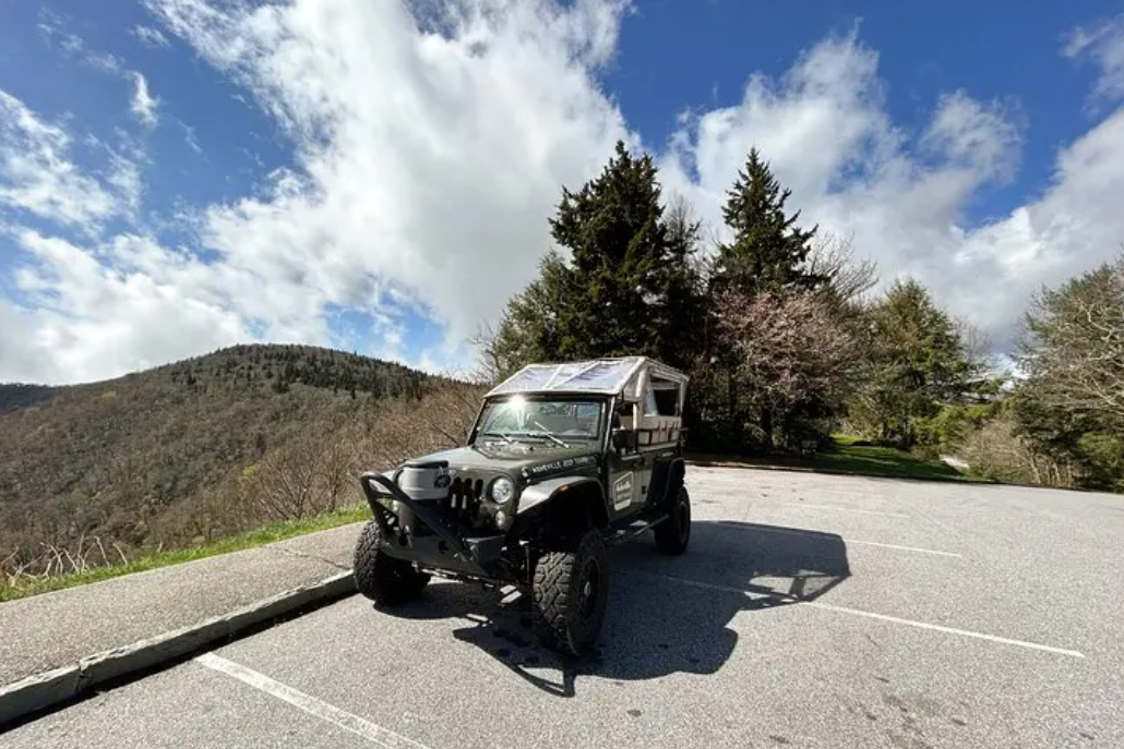 A jeep is parked in a parking lot on top of a hill.