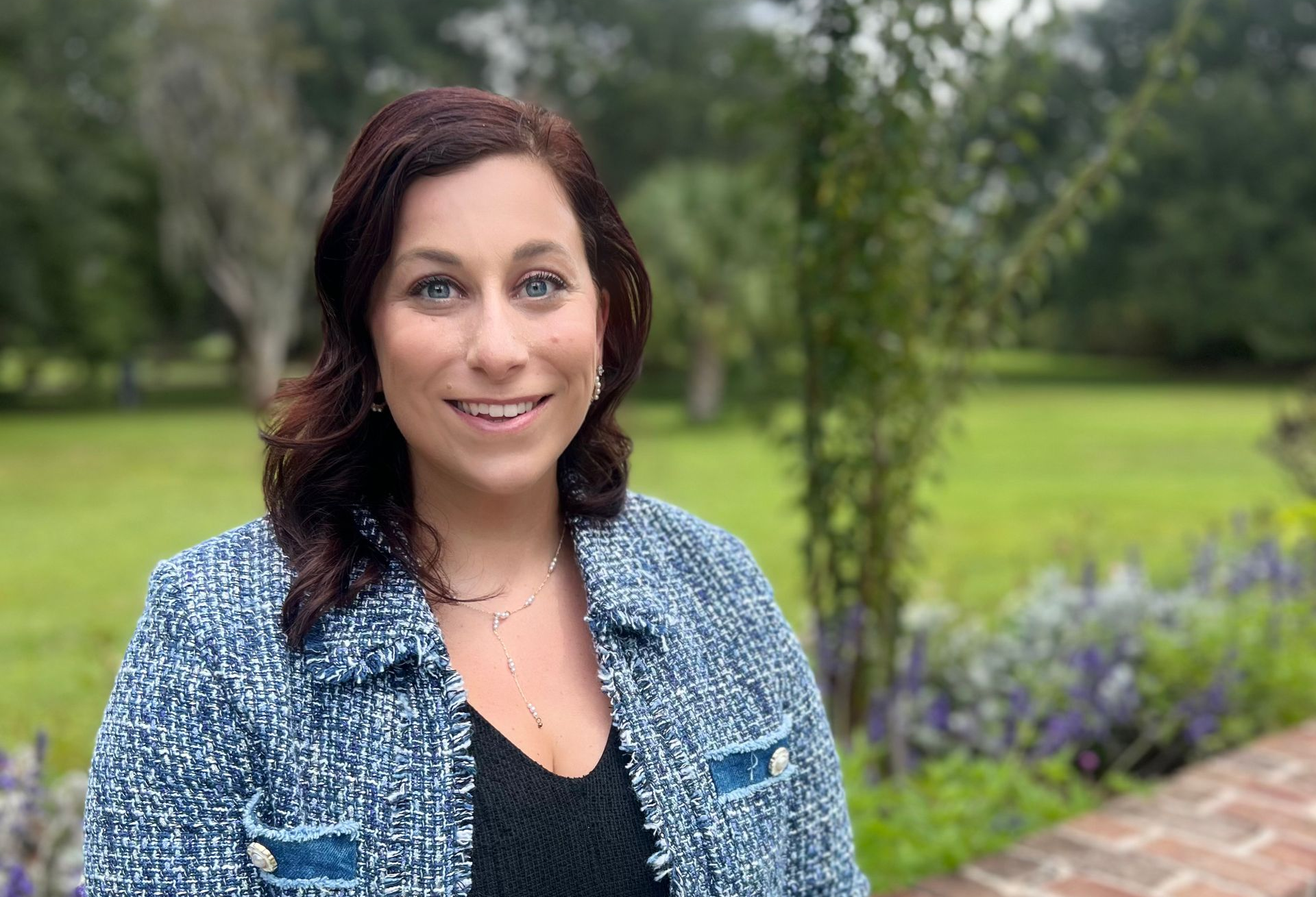 Emily Gates  smiles outside in a blue patterned jacket.