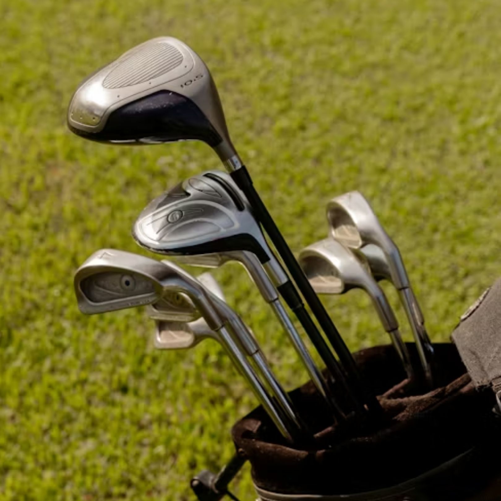 A set of golf clubs in a dark bag, standing on a bright green lawn.
