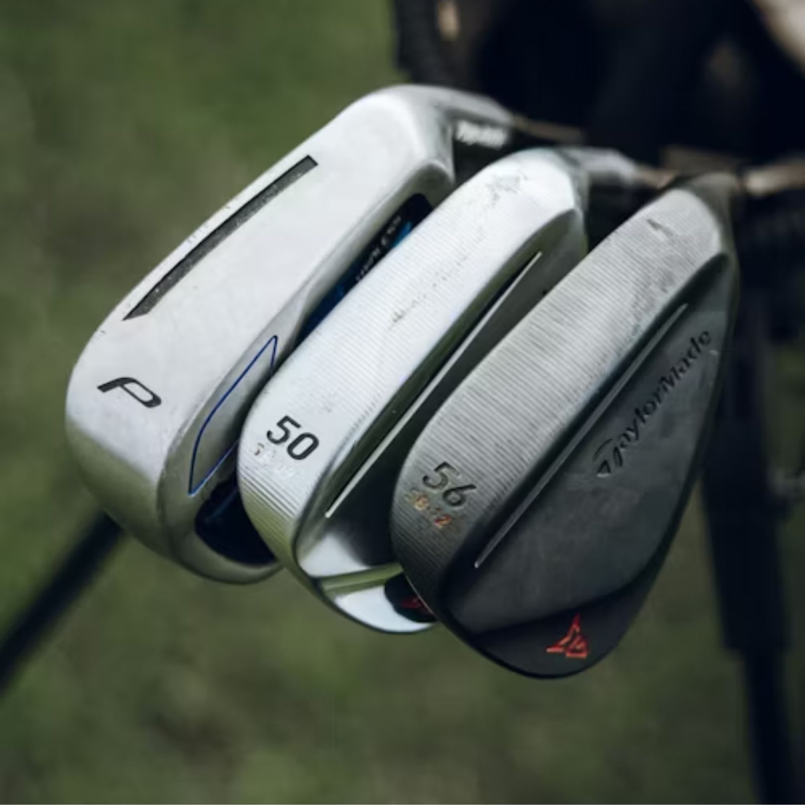 Three golf clubs arranged in a bag: a P-wedge, a 50-degree gap wedge, and a black 56-degree sand wedge by TaylorMade.