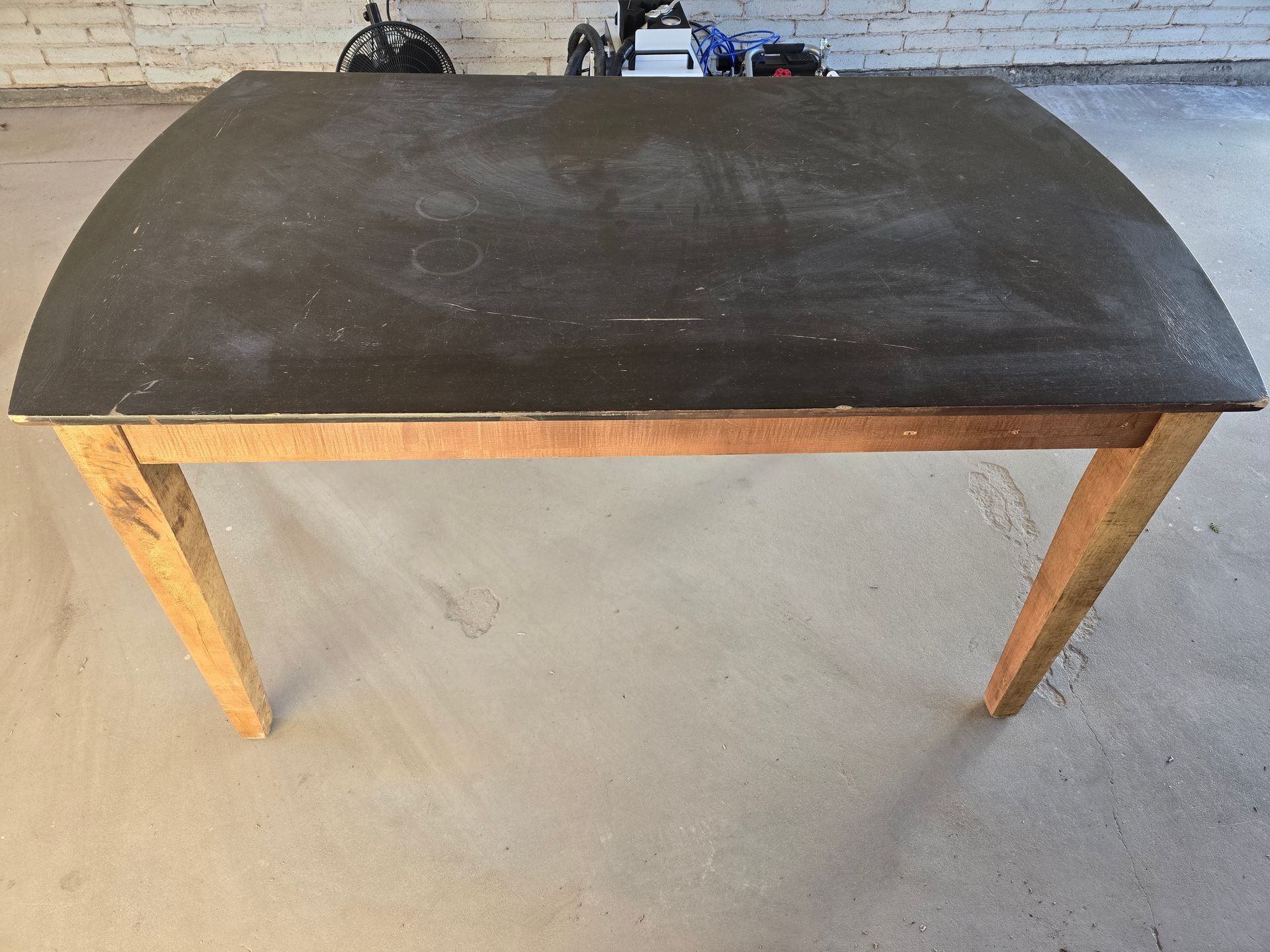 Thick paint and poly finish on a dinner table top, removed to reveal natural grain of the bare wood.