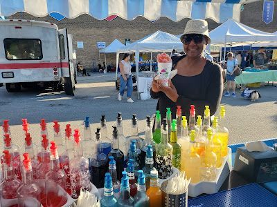 A woman is standing in front of a table holding a cup of ice cream.