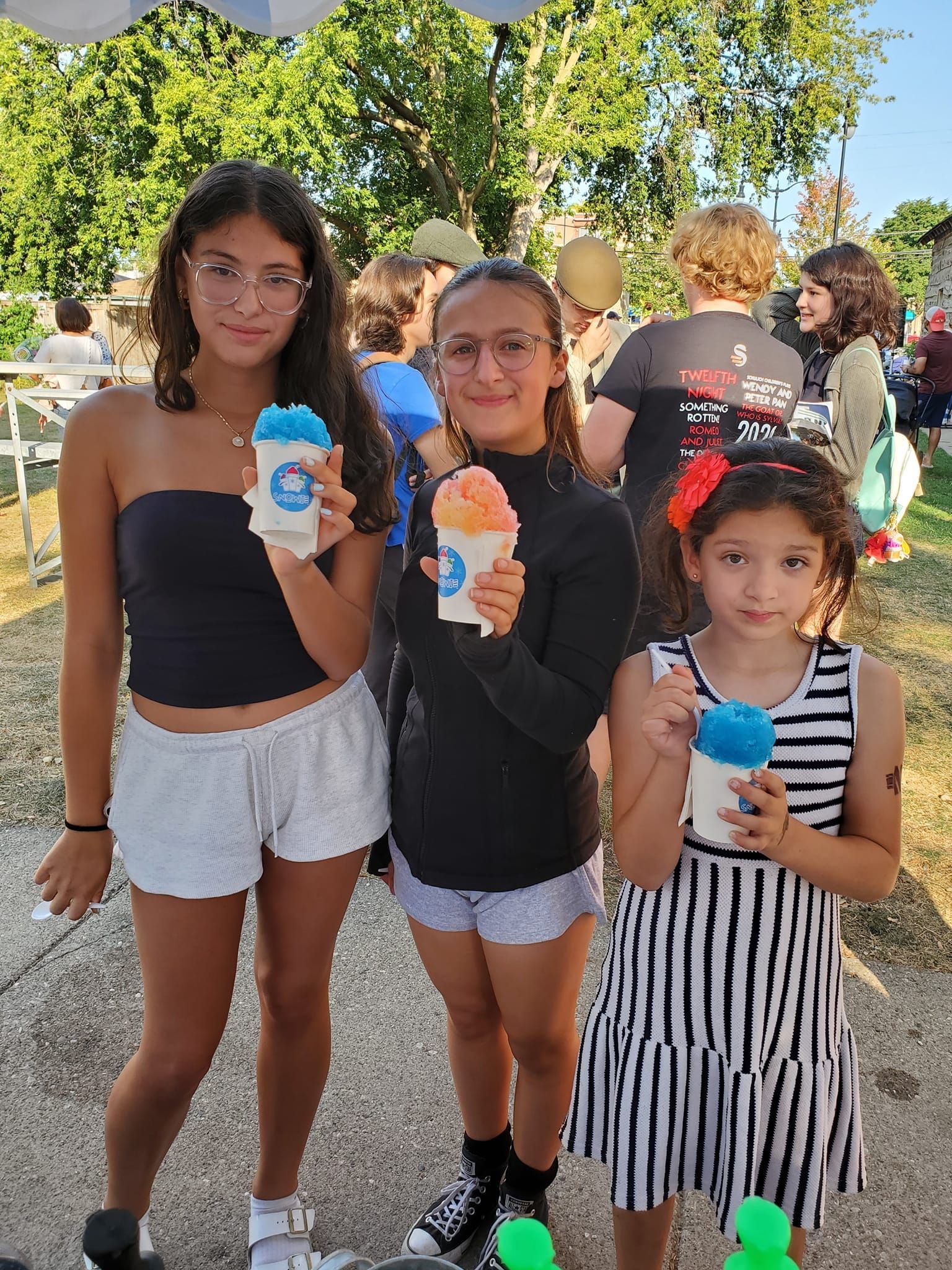 Three young girls are standing next to each other holding ice cream cones.