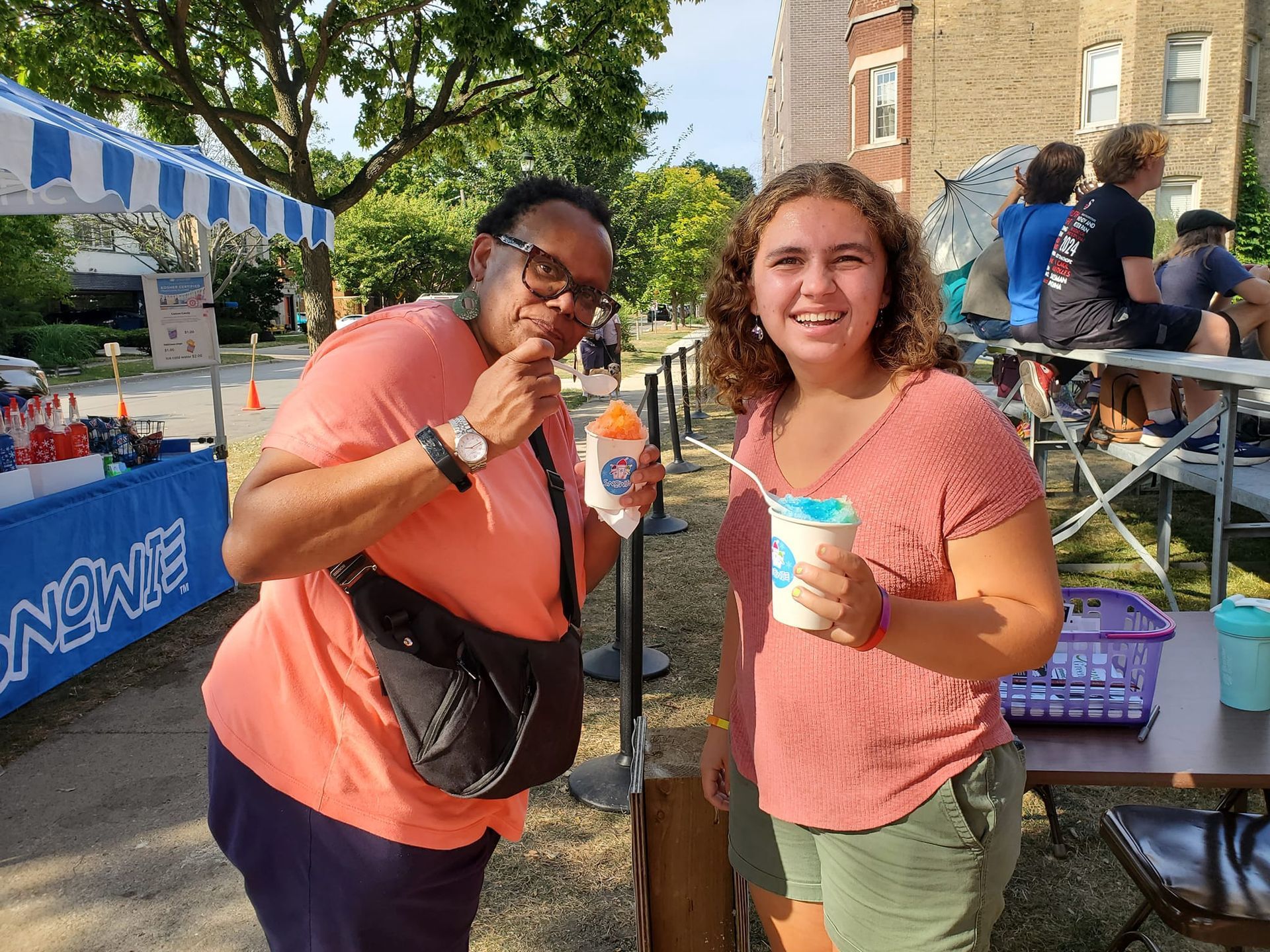 Two women are standing next to each other eating ice cream.