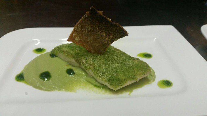 Ein weißer Teller mit einem Stück Essen und grüner Soße.