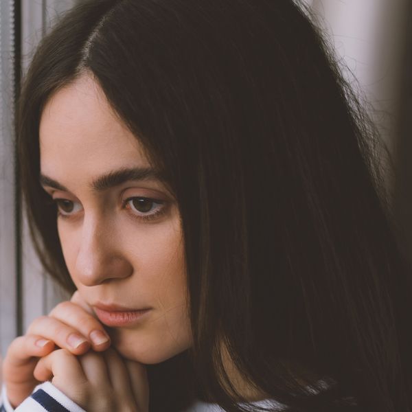 woman with anxiety staring out the window with a blank look on her face