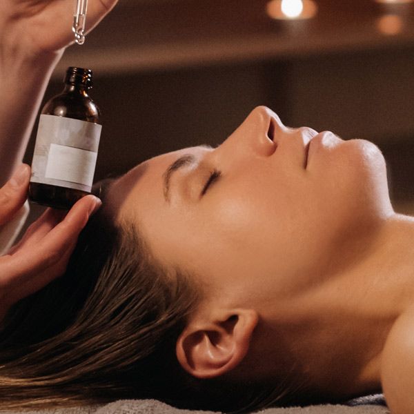 A woman is getting an aroma healing treatment with a bottle of scented oil near her face