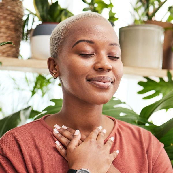 A woman with her eyes closed is holding her hands to her chest representing Sushumma, Ida, and Pingala Balancing 