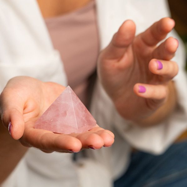 A woman is holding a pink pyramid in her hands representing Pyramid Therapy