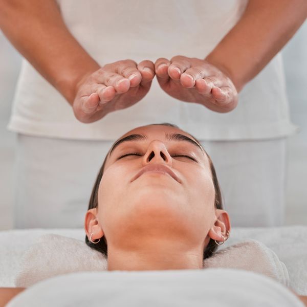 A woman is getting a Reiki session with her eyes closed.