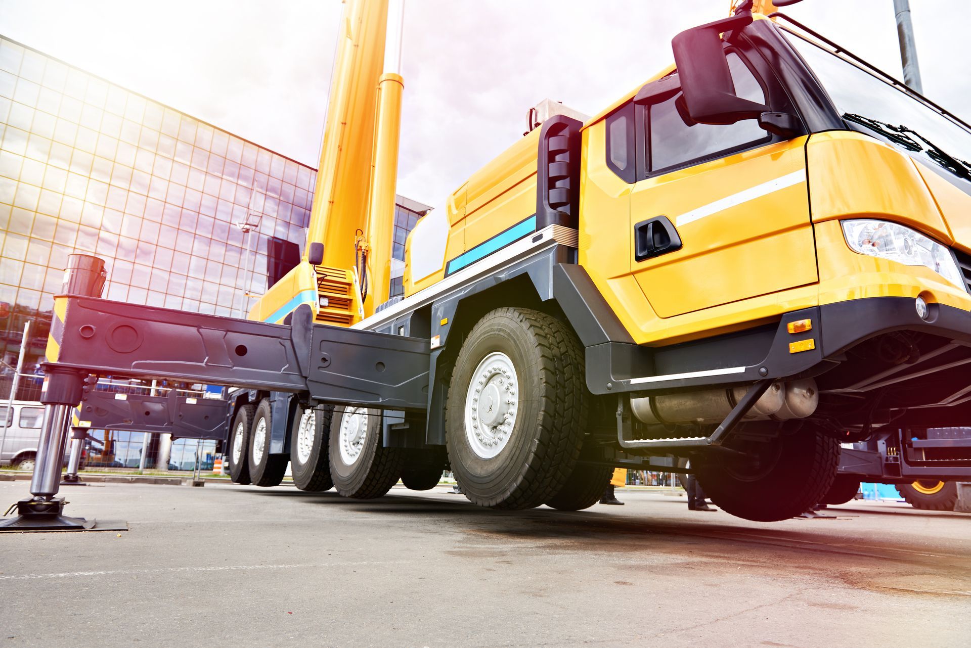 Un camion-grue mobile jaune, ses stabilisateurs déployés et stabilisé sur une surface asphaltée.