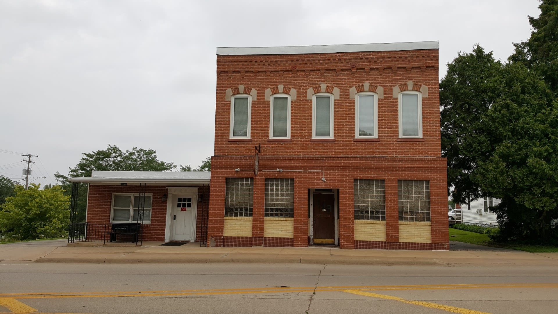 A brick building with a lot of windows is sitting on the side of the road.