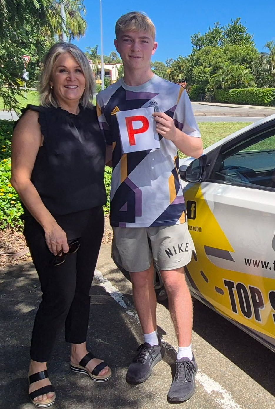 A Woman is Standing Next to a White Car — Top Start Driving School In Cannonvale, QLD

