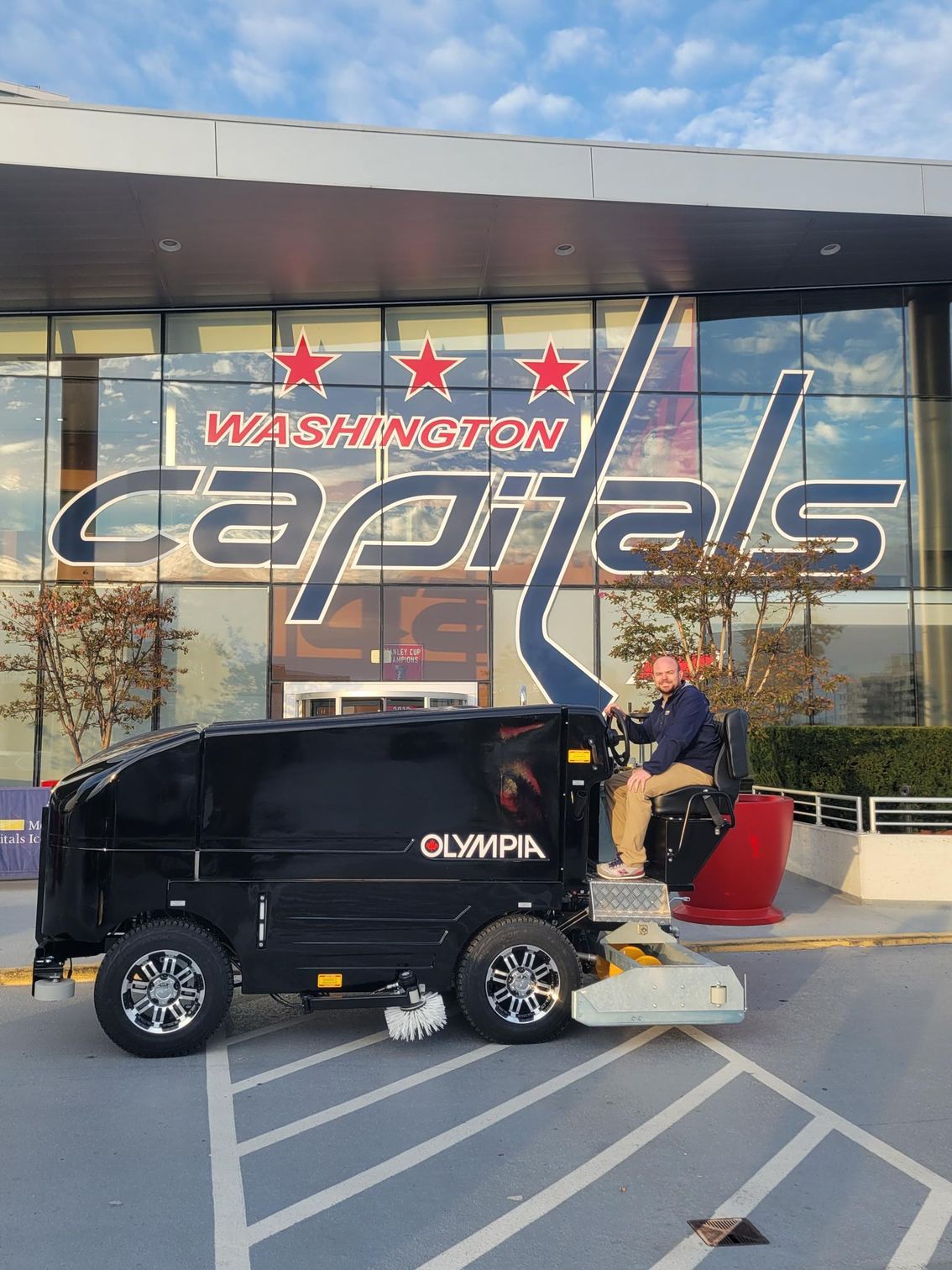 A man is riding a scooter in front of a washington capitals building.