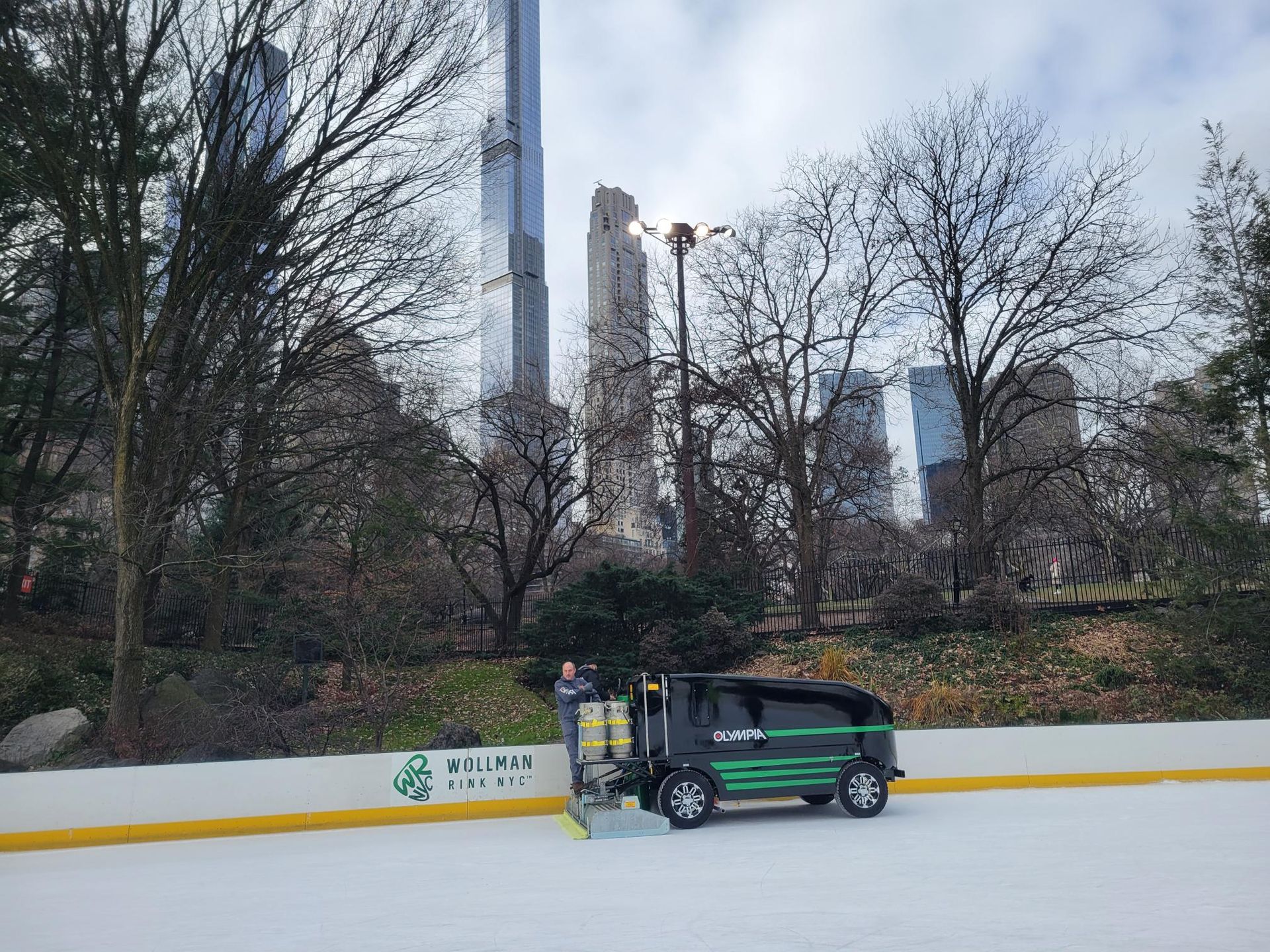 A car is parked on the ice rink in a park.