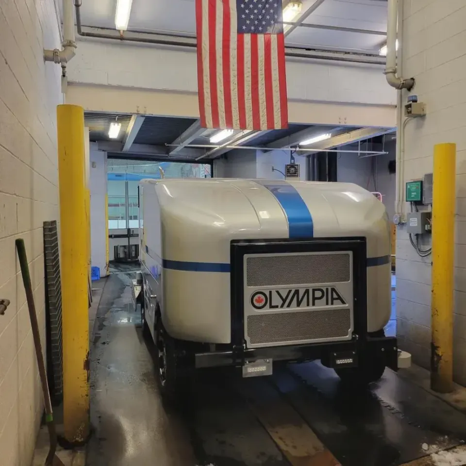 A white olympia vehicle is parked in a garage