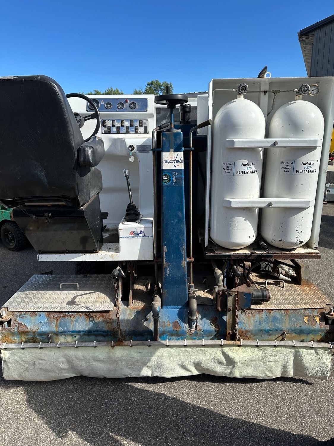 A machine with two cylinders attached to it is parked on the side of the road.