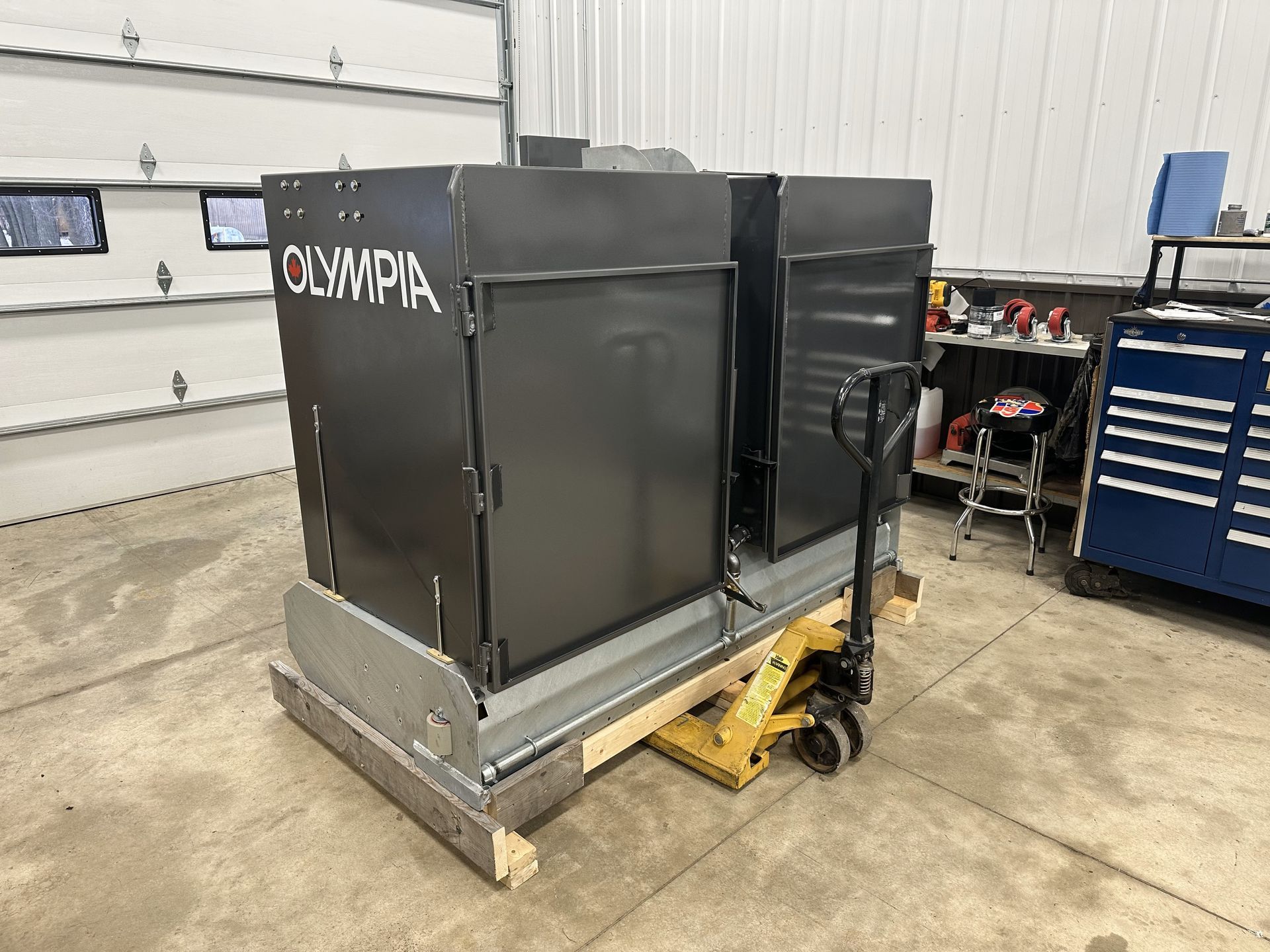 A machine is sitting on a pallet in a garage.