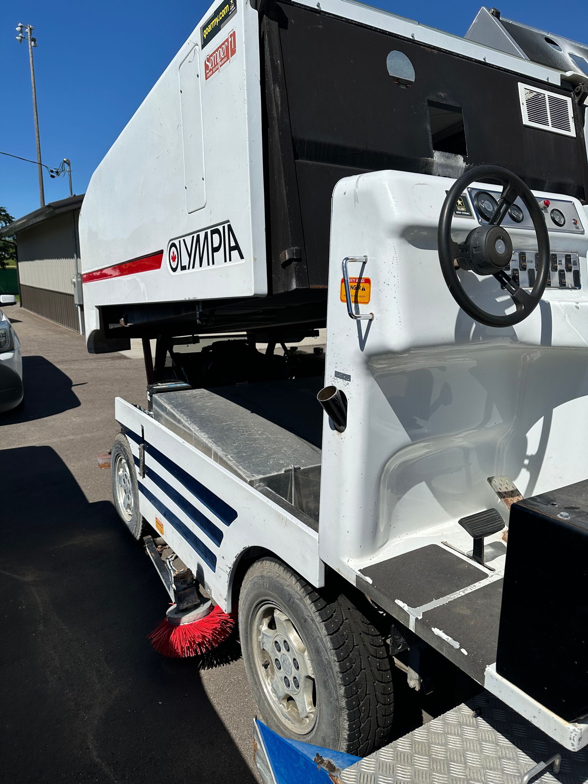 White vehicle with attached simulator, parked outdoors. 