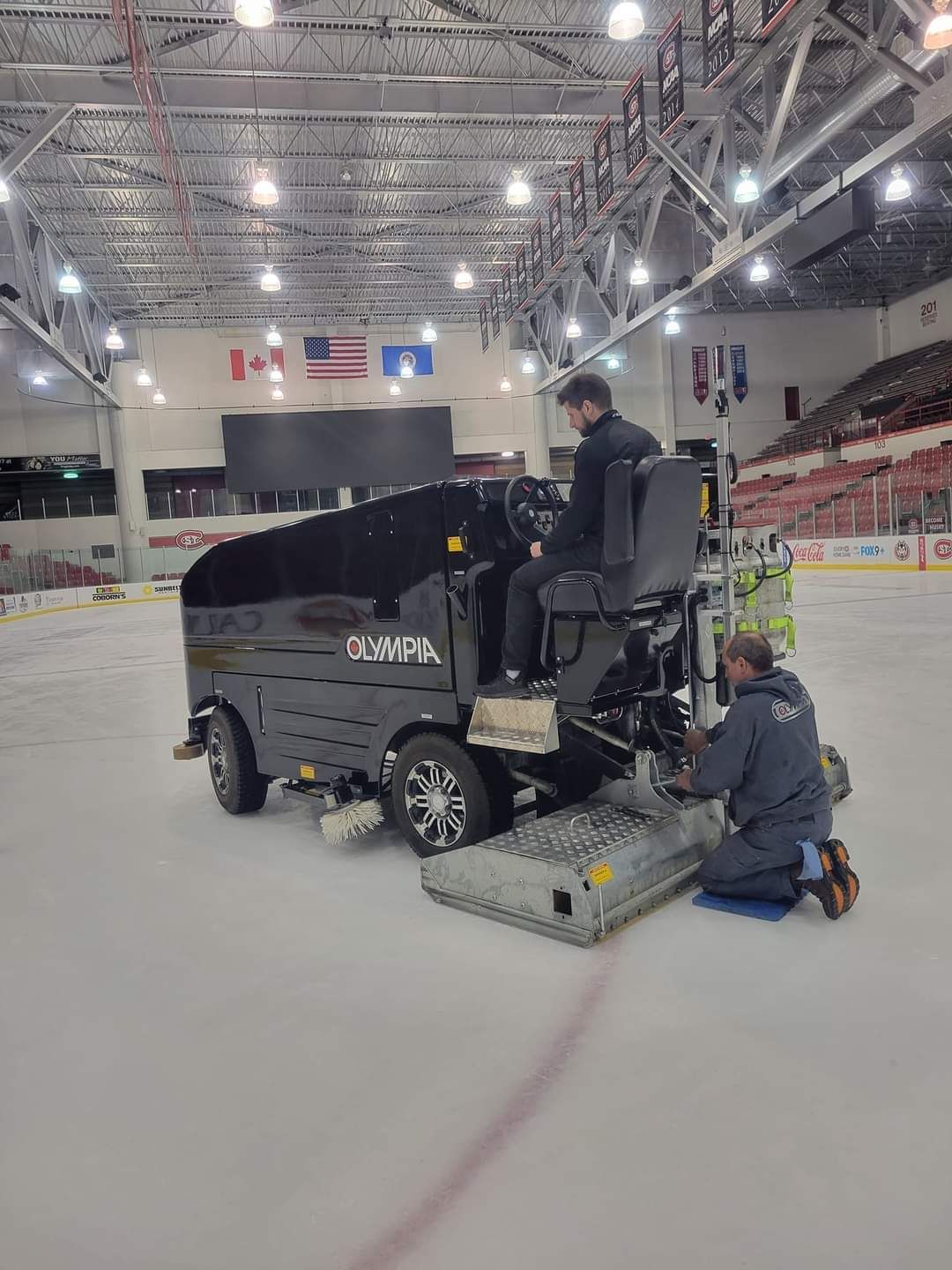 Two men are working on an ice hockey rink.