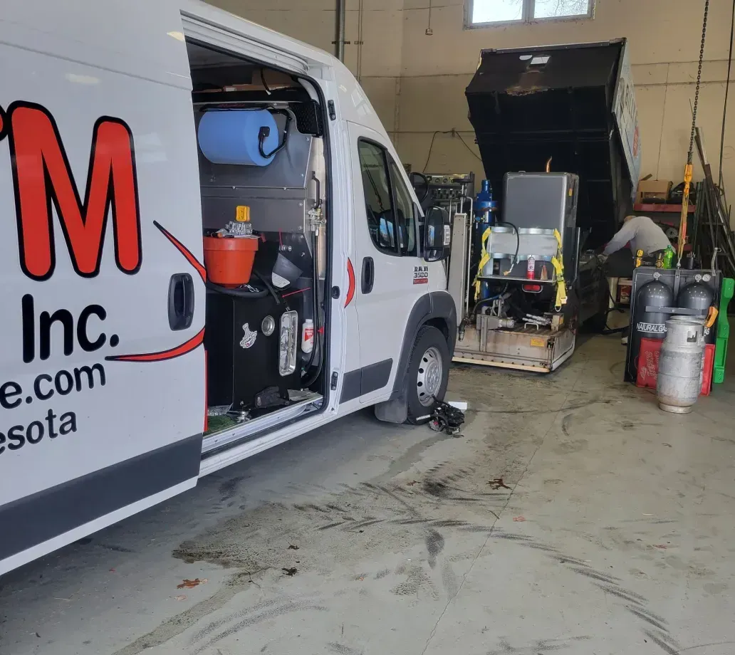 A white van with the word m on it is parked in a garage.