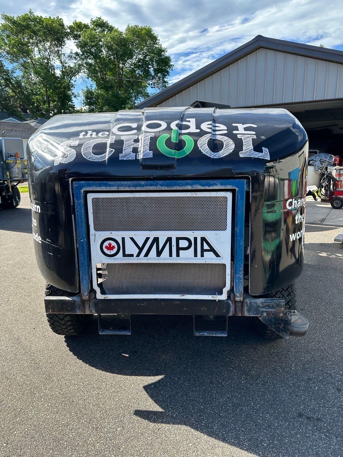 A black trailer with olympia written on it is parked in front of a building.