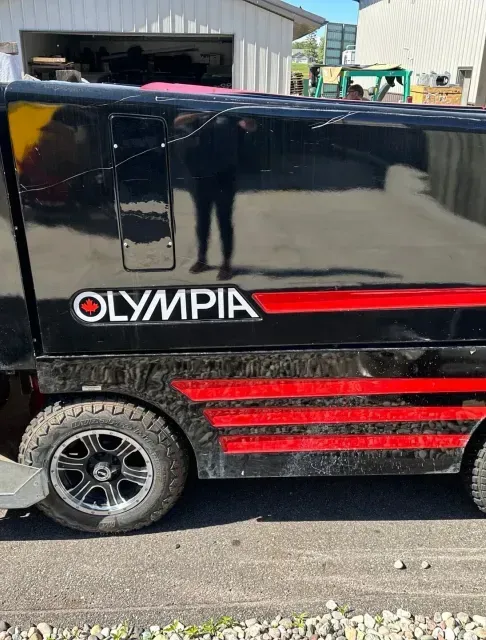 A black and red olympia vehicle is parked on the side of the road.