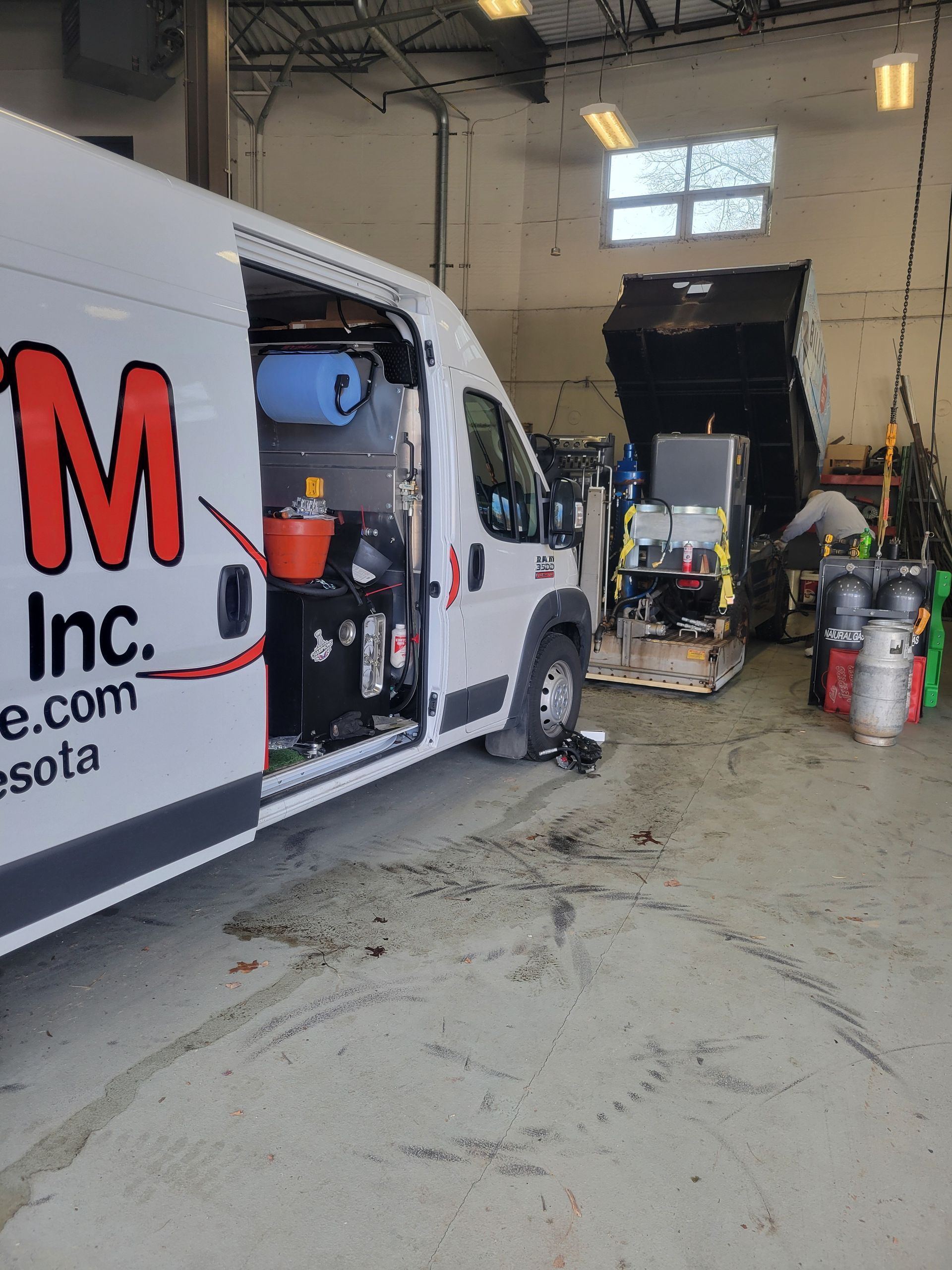 A white van with the word m on it is parked in a garage.