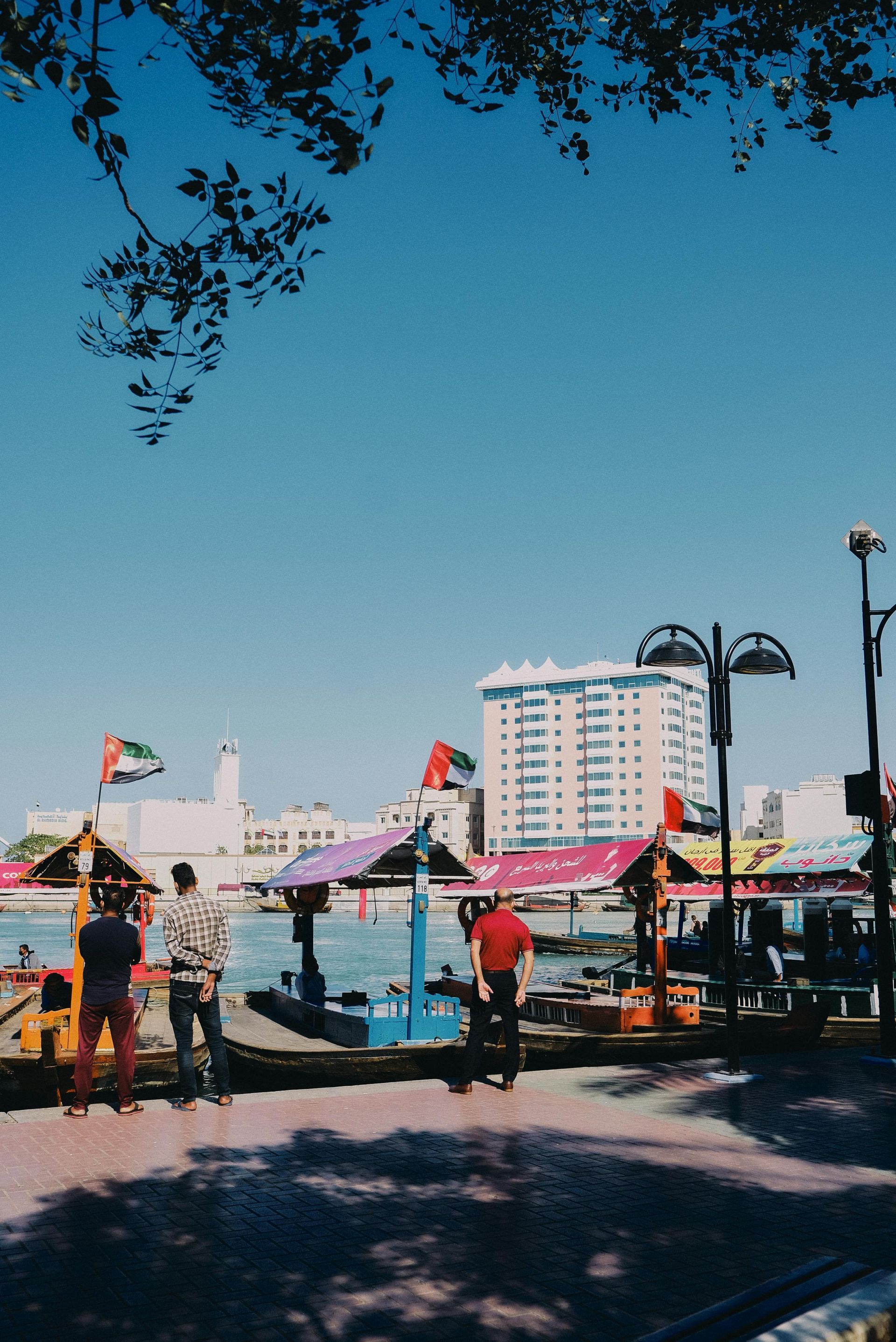 A group of people standing on a sidewalk near a body of water