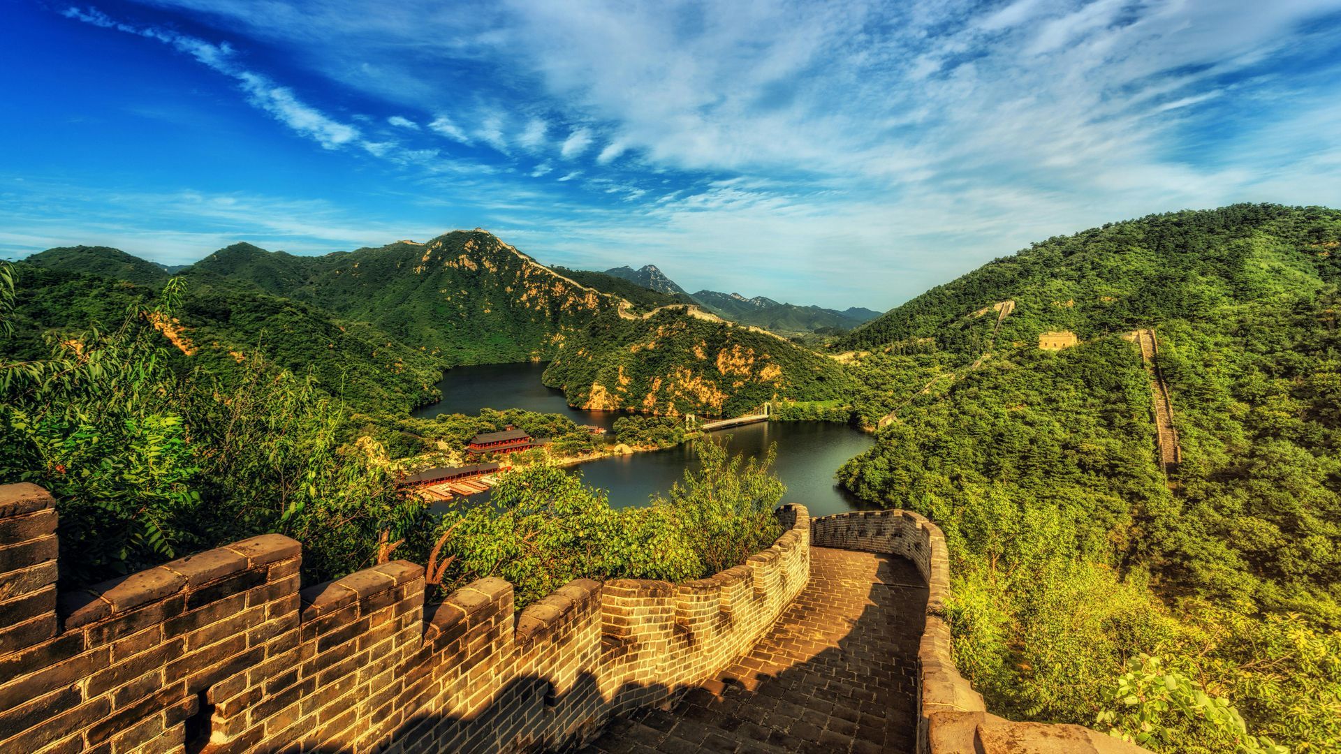 The great wall of china is surrounded by mountains and trees.
