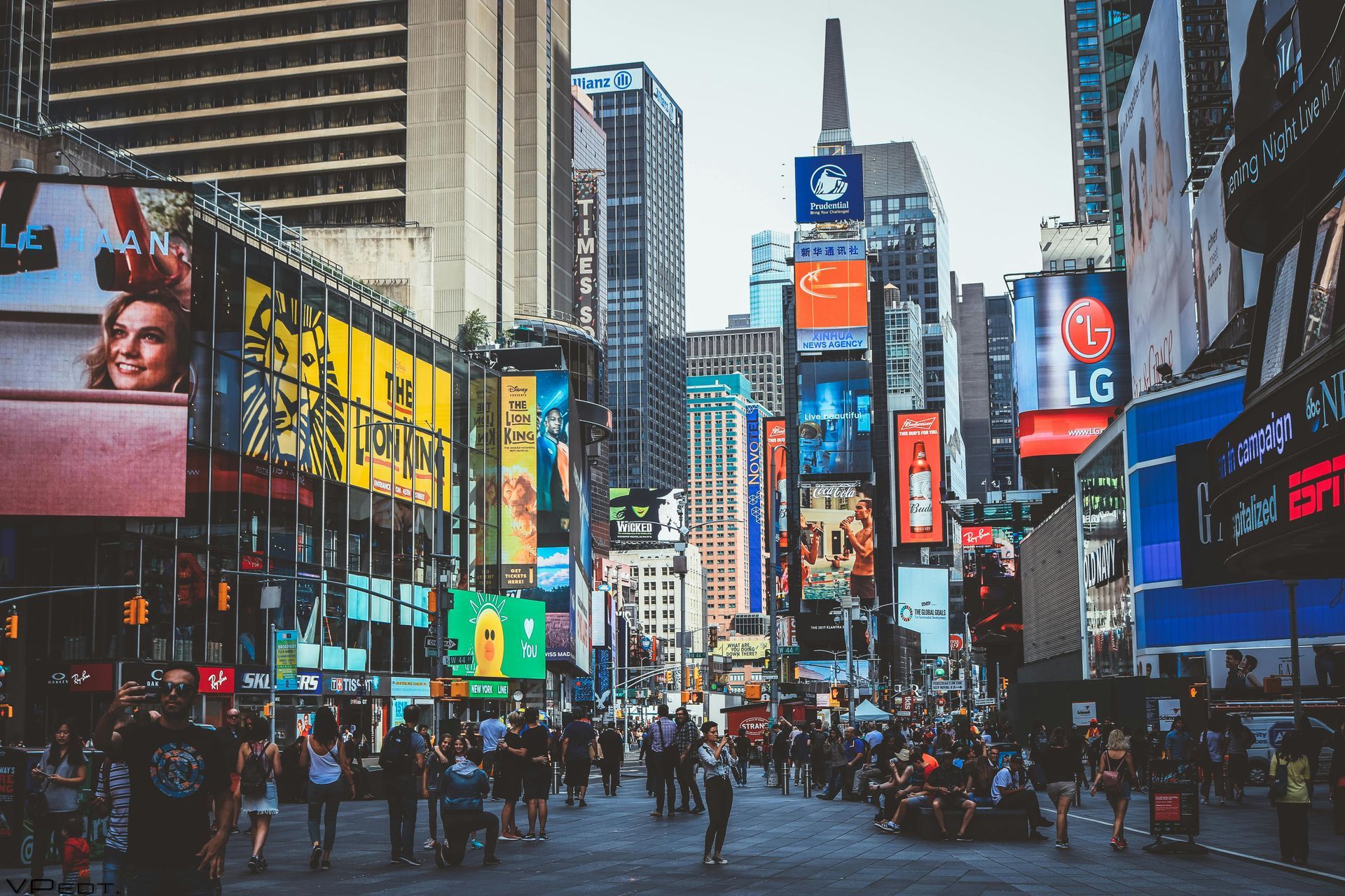 A crowd of people are walking down a busy city street.