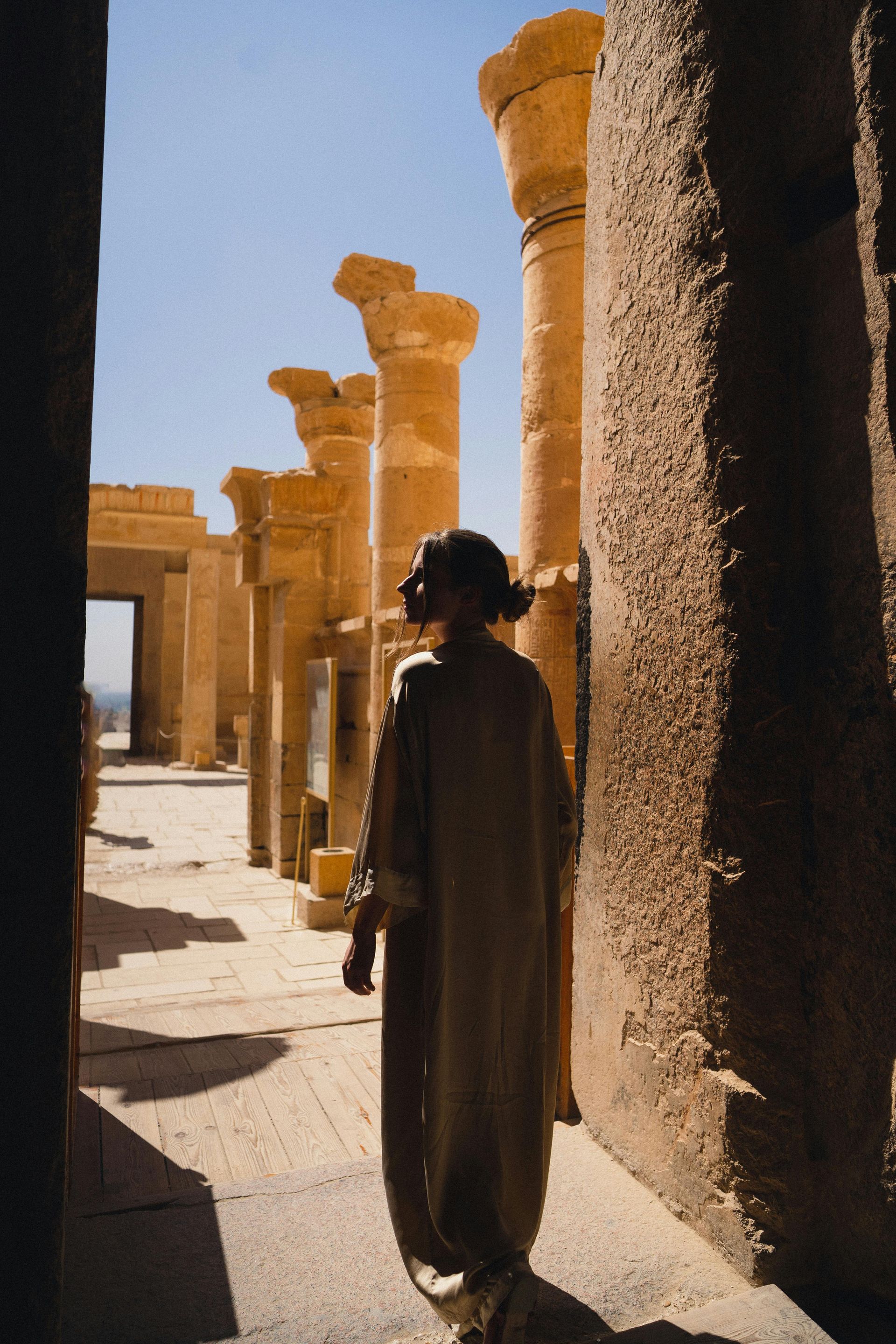 A woman is standing in a hallway between two columns.