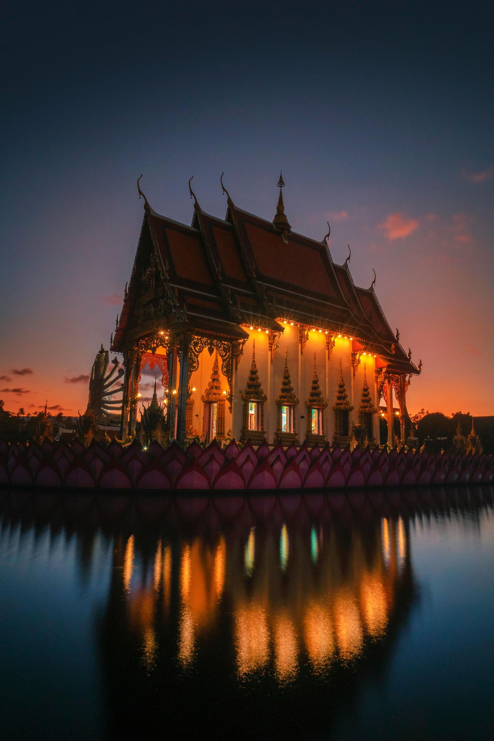 A temple is reflected in the water at sunset.