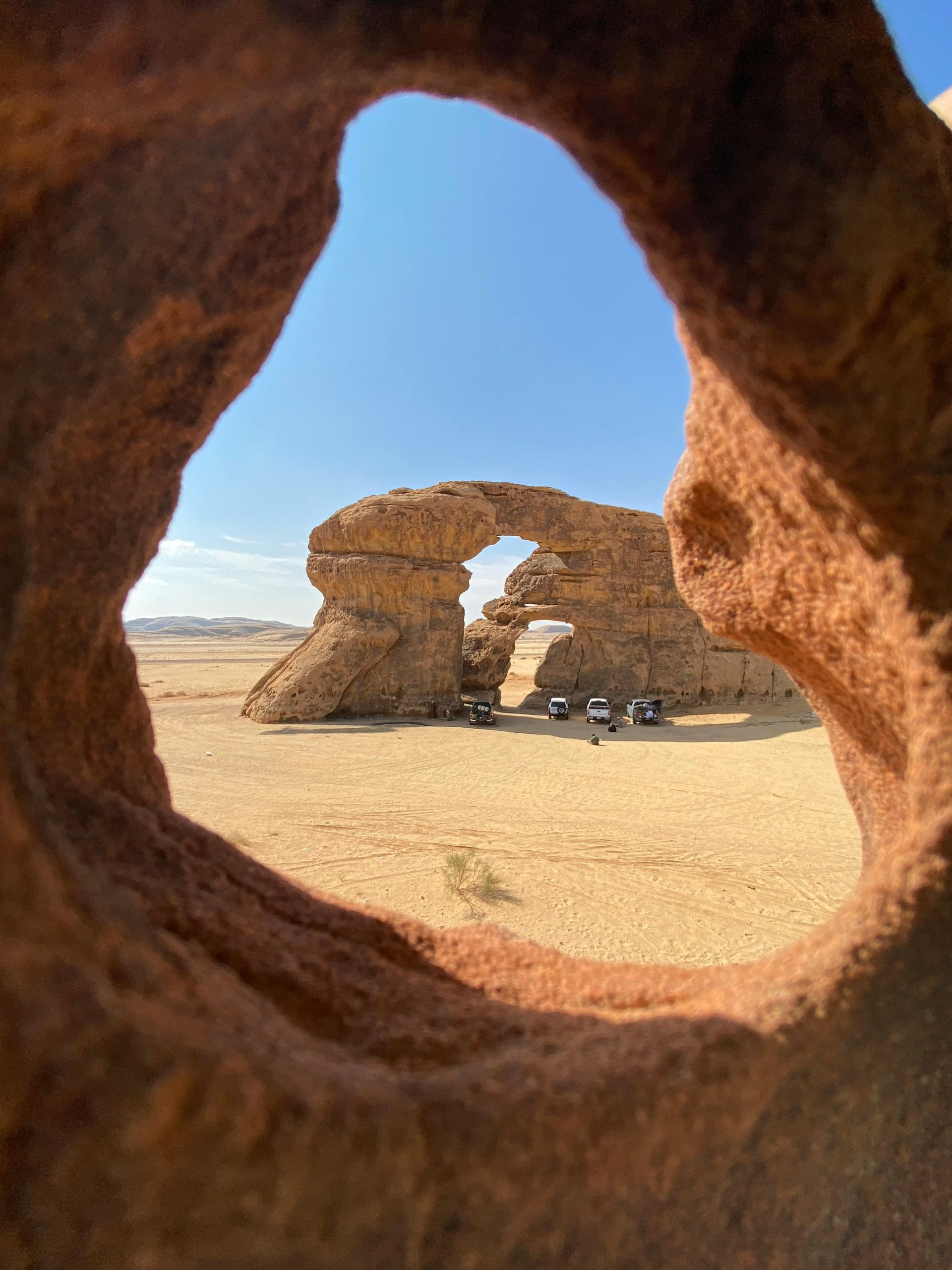 A view of a desert through a hole in a rock.